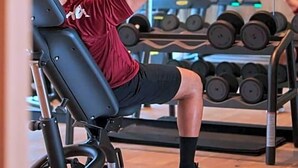 Ein Fitnessraum mit Trainingsgeräten, darunter eine Bank und Kurzhanteln.