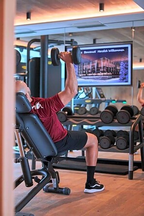 Un gimnasio con equipo de ejercicio, incluyendo una banca y mancuernas.