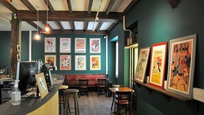 A restaurant interior with a counter, seating area, and wall-mounted posters. - Hostel 20 Bayonne (Bayonne)