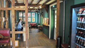 Ein Restaurant mit Holzbalken, einer Bar und gerahmten Kunstwerken an den Wänden.
