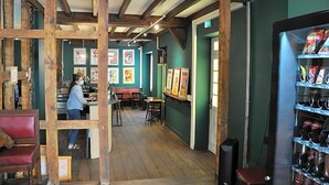 A restaurant with wooden beams, a bar area, and framed artwork on the walls. - Hostel 20 Bayonne (Bayonne)
