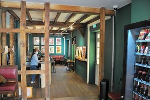 En restaurant med træbjælker, en bar og billeder i rammer på væggene.