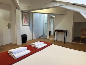 A hotel room with a bed, a red rug, a small table, and a mirror. - Hostel 20 Bayonne (Bayonne)
