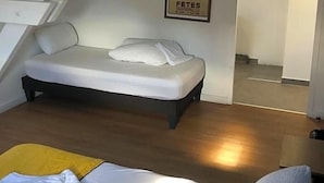 Ein Schlafzimmer mit einem Bett, einem kleinen Tisch, einem Stuhl, einer Treppe und einer Tür zu einem anderen Raum.