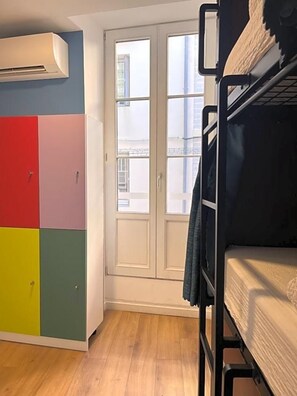 A room with a bunk bed, a colorful wardrobe, and a window with a view of buildings. - Hostel 20 Bayonne (Bayonne)