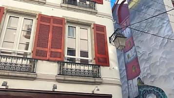 Un immeuble avec des volets rouges, un balcon et une grande fresque murale.