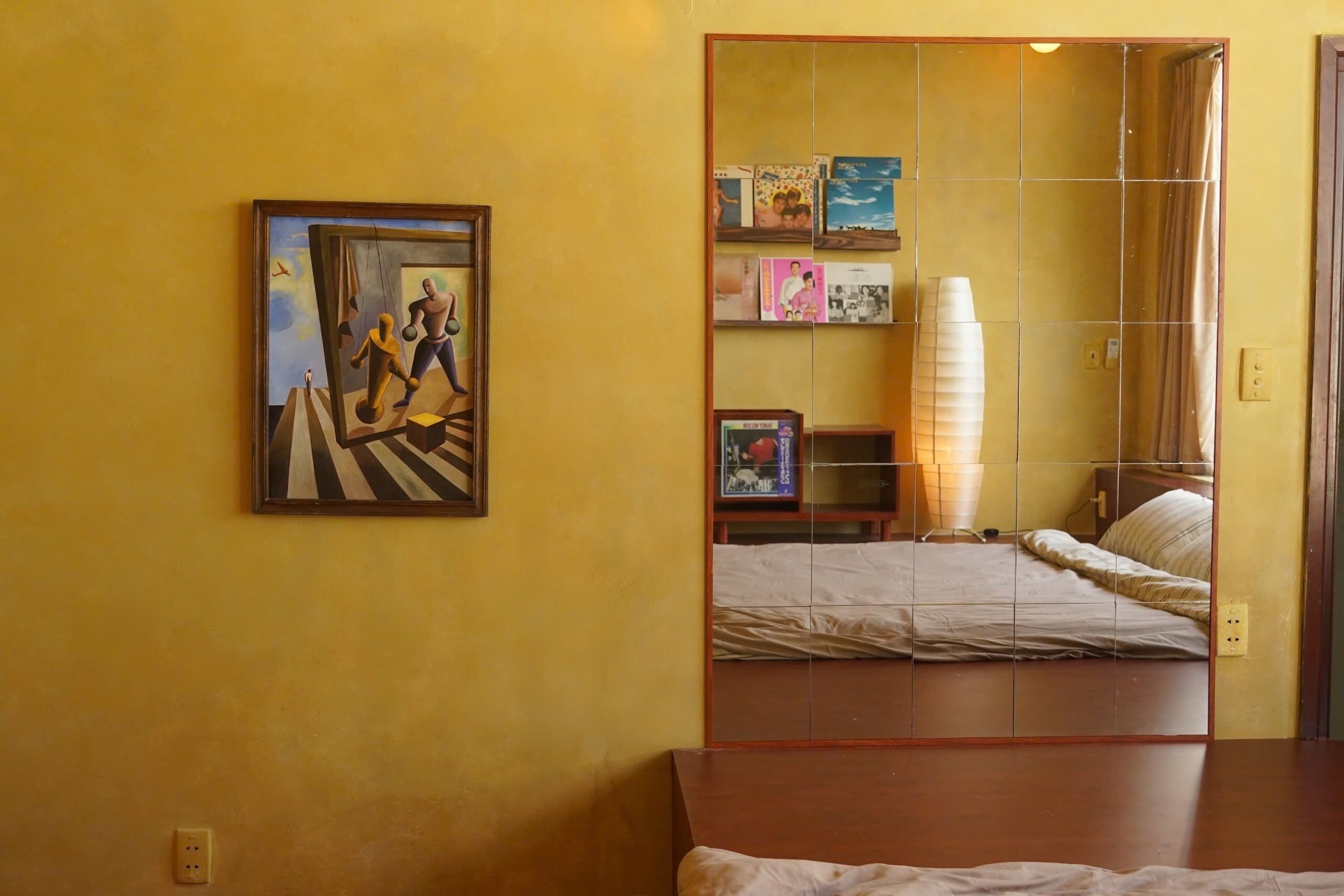 Habitació d'hotel amb un llit, una tauleta de nit, un mirall i un quadre a la paret.