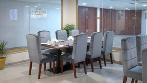 Una sala de conferencias con una mesa redonda, sillas tapizadas en gris y suelo de madera.