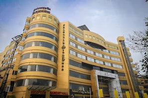 Un hotel de varios pisos con fachada curva, zona de recepción y salón de banquetes.