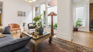 Een woonkamer met een bank, fauteuil, salontafel en potplanten.