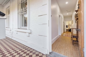 A hallway with a checkered floor, white walls, and a wooden door. - Storied terrace opposite Carlton Gardens (Carlton)