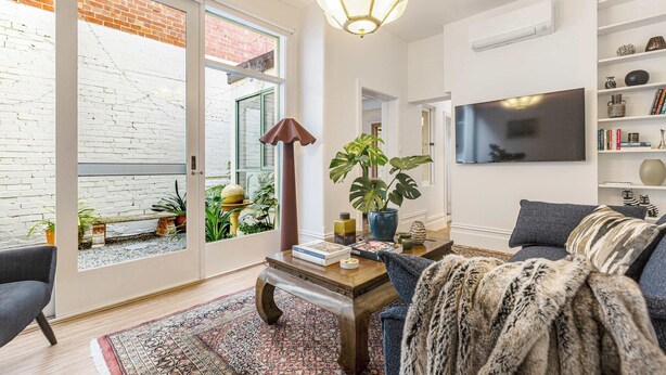 Een woonkamer met een bank, een salontafel, een televisie en een boekenkast.
