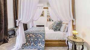 Een slaapkamer met een hemelbed, een nachtkastje met een lamp en een klein houten nachtkastje.