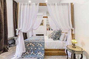 A bedroom with a canopy bed, a bedside table with a lamp, and a small wooden nightstand. - Storied terrace opposite Carlton Gardens (Carlton)