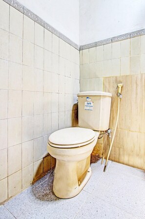 Un baño con inodoro, paredes de azulejos y panel de madera.