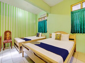 A room with two beds, a chair, a desk, and a window with curtains. - Spot On 93182 Hotel Jaya Kusuma (Prambanan)
