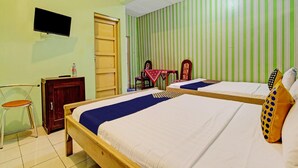 Ett hotellrum med två sängar, en tv, ett träskåp, en stol och en randig vägg.