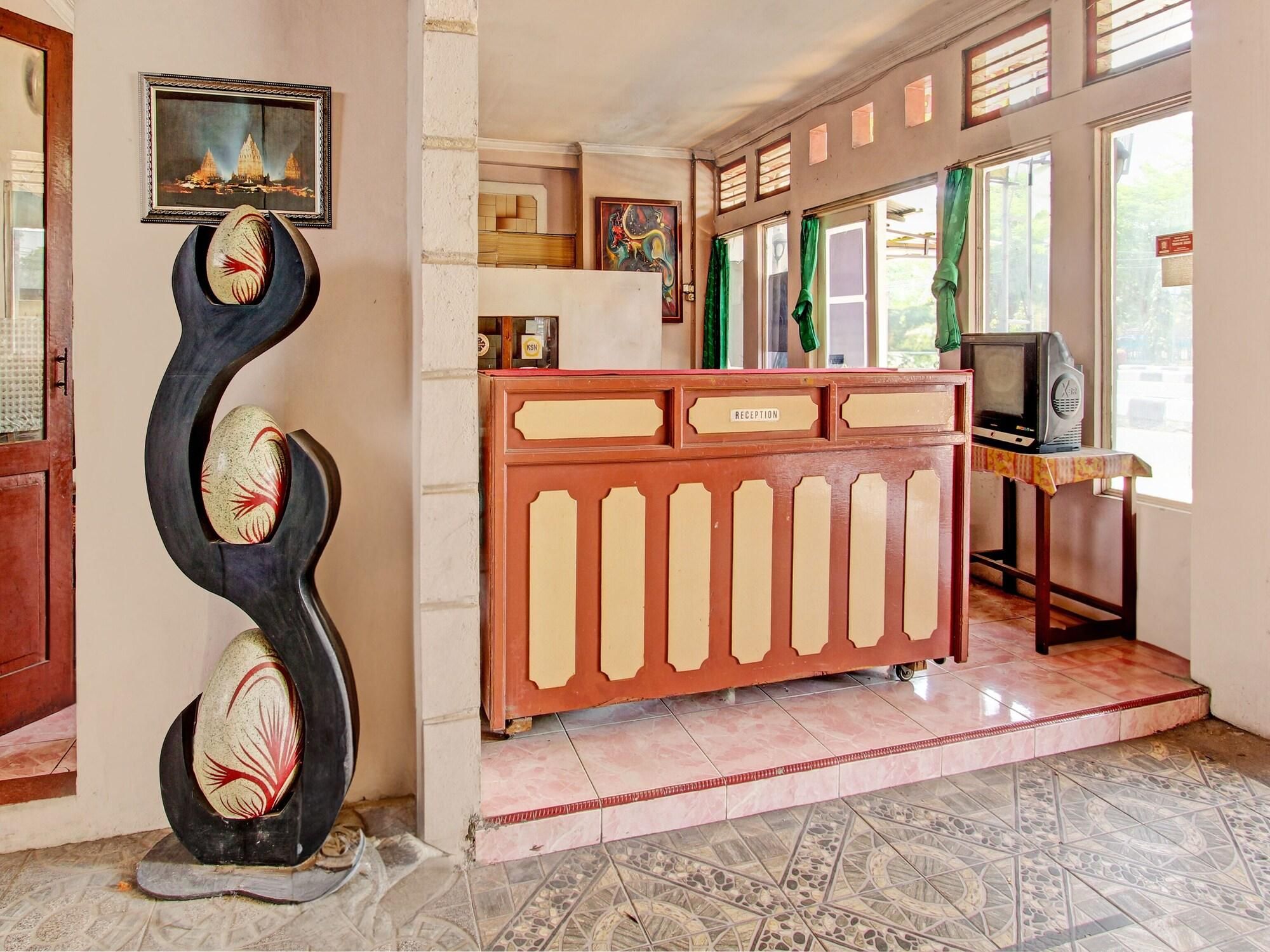 A reception area with a reception desk, a television, and a decorative sculpture.