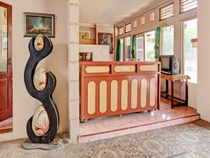 Een ontvangsthal met een receptiebalie, een televisie en een decoratieve sculptuur.