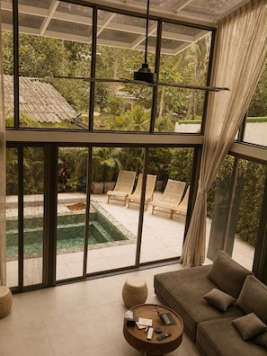 Un interior moderno con ventanas amplias, una piscina y mobiliario exterior.