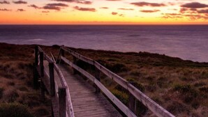 A wooden boardwalk leading to a beach with a sunset in the background. - See U Inn (Murtosa)