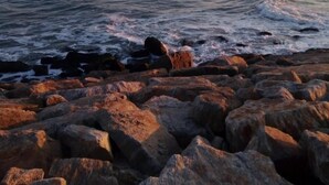 Uma costa rochosa com ondas quebrando nas pedras.