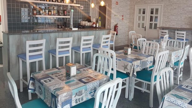 A restaurant with a bar area, multiple tables with chairs, and a tiled backsplash. - See U Inn (Murtosa)