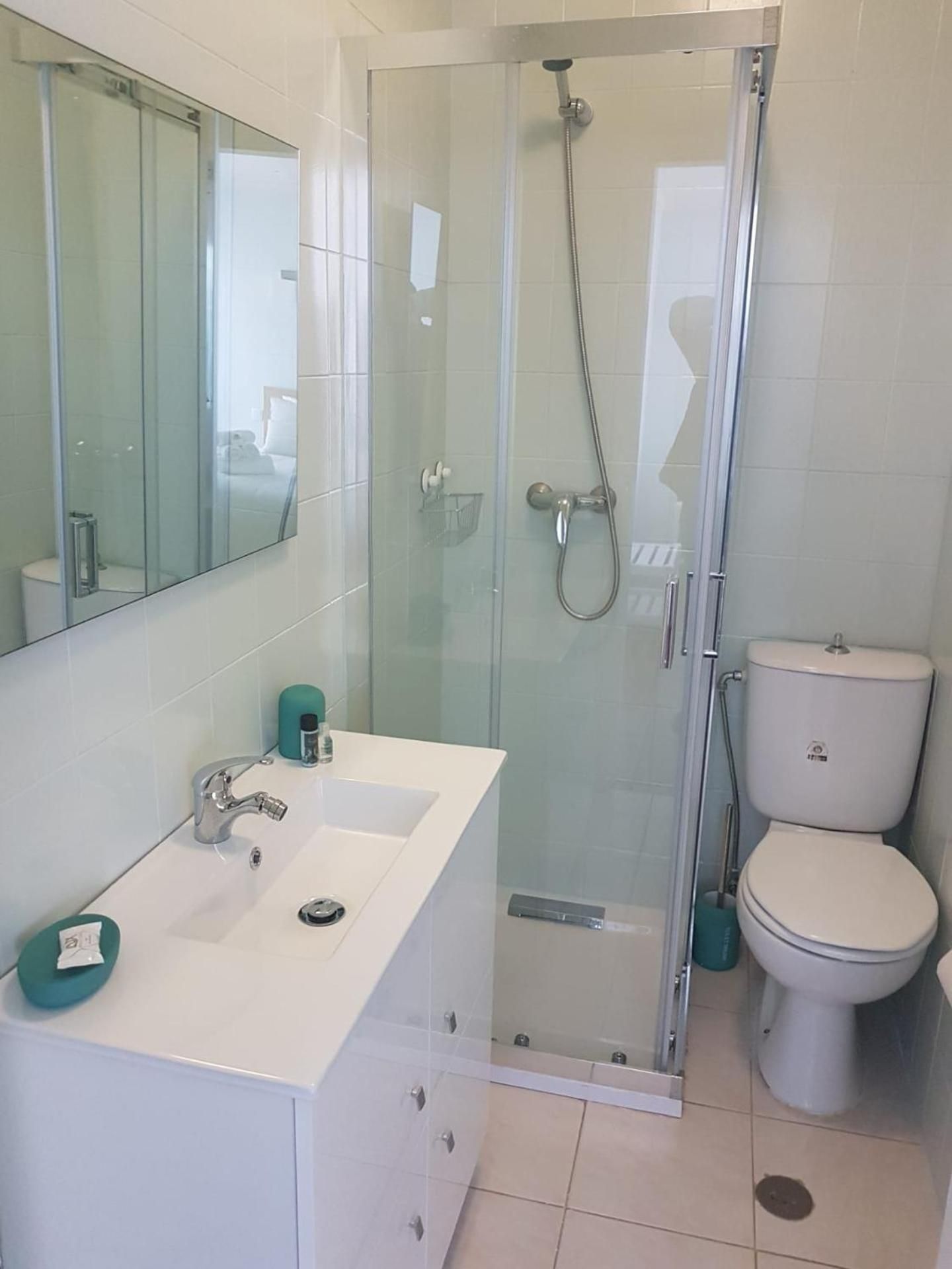 A modern bathroom with a glass-enclosed shower, a white sink with a mirror above, and a toilet.