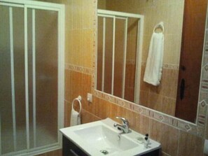 Un baño con lavamanos blanco, un espejo y un perchero para toallas.