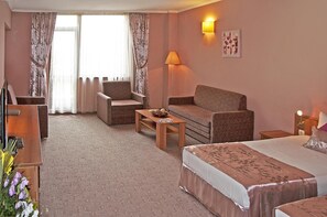A hotel room with a bed, two armchairs, a sofa, a small table, a lamp, and a painting on the wall. - Hotel Real (Plovdiv)