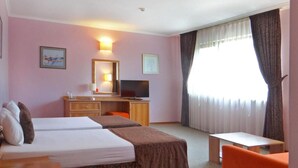Une chambre d’hôtel avec deux lits, un bureau, une télévision et une petite table.