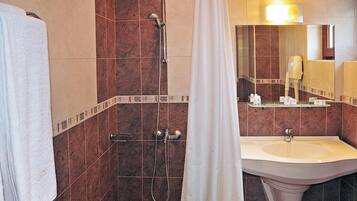 A bathroom with a shower, a sink, and a mirror.