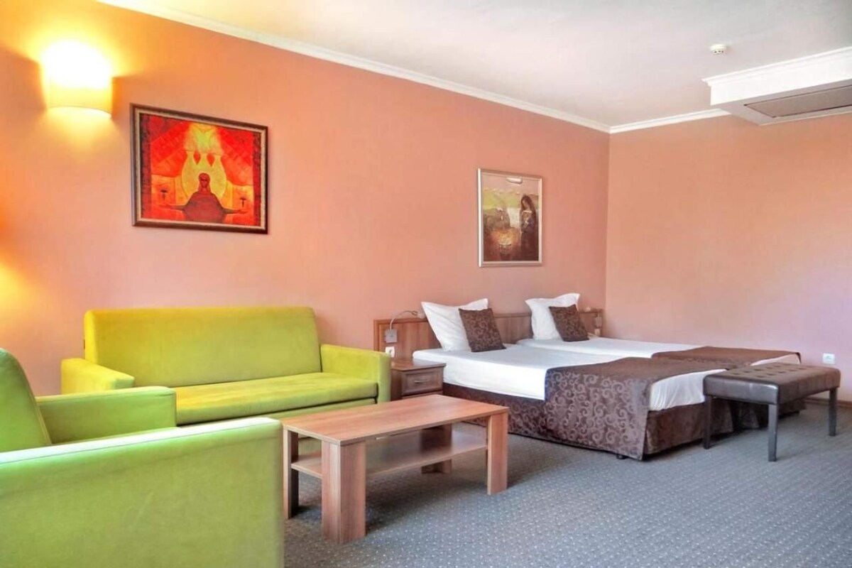 A hotel room with a bed, a sofa, a chair, and a small table.