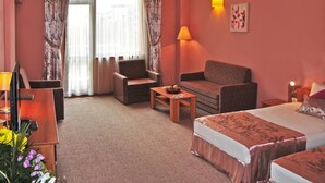 Une chambre d’hôtel comprenant un lit, deux fauteuils, un canapé, une petite table et une lampe.