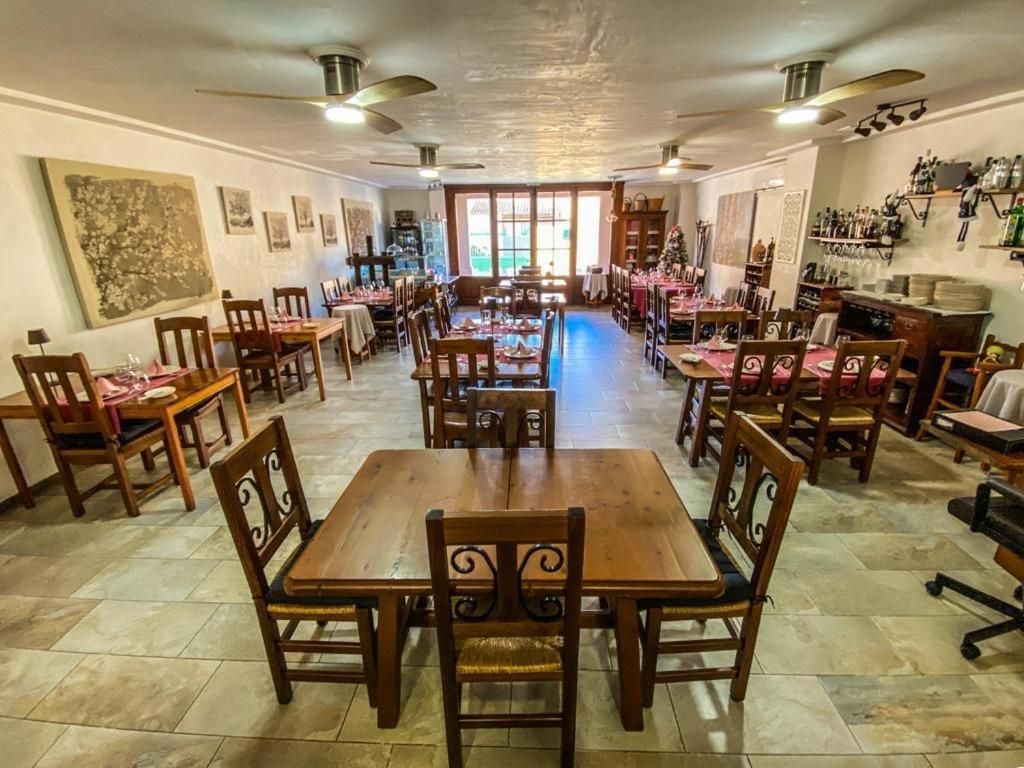A restaurant with multiple dining tables and chairs, a tiled floor, and ceiling fans.