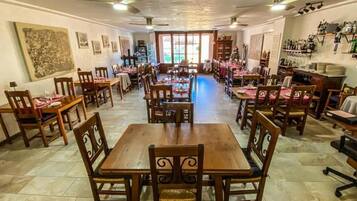 A restaurant with multiple dining tables and chairs, a tiled floor, and ceiling fans.