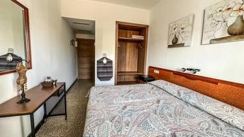 A hotel room with a bed, a desk, a mirror, and a wardrobe.