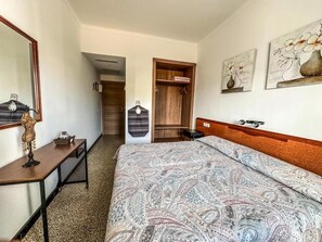 Una habitación de hotel con cama, escritorio, espejo y armario.