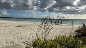 Uma praia com céu claro e algumas nuvens.