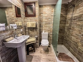 Un baño con lavamanos, inodoro y zona de ducha.