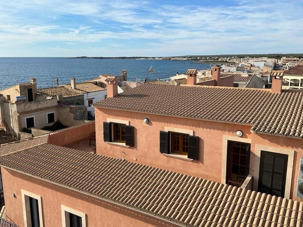 A coastal residential area with terracotta-tiled rooftops and a view of the sea.