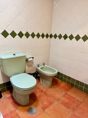 Une salle de bain équipée de toilettes, d’un bidet et d’un porte-rouleau de papier toilette.