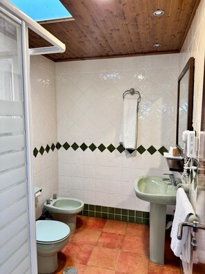 A bathroom with a wooden ceiling, a toilet, a bidet, and a sink. - El Eden (El Ejido)