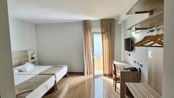 A hotel room with two beds, a desk, a chair, a TV, and a wardrobe.