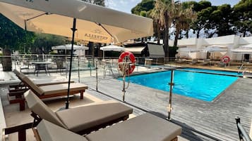 A poolside area with lounge chairs, umbrellas, and a lifebuoy.