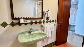 A bathroom with a sink, mirror, towel rack, and a door leading to another room.