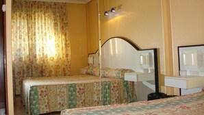 A hotel room with two beds, a bedside table, a mirror, and a small desk with a lamp. - Motel Cancun Barbadas Ourense (Barbadas)