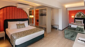 Ett hotellrum med en säng, ett skrivbord, en grön fåtölj, en garderob och en röd accentvägg.