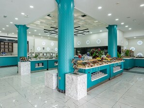 A modern hotel lobby with a buffet area, marble flooring, and teal-colored pillars. - La Benata Beach Hotel (Manavgat)