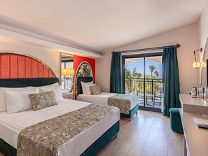 Une chambre d’hôtel avec deux lits, un balcon offrant une vue agréable et un bureau avec une lampe.